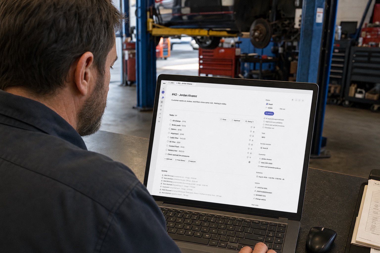 Service advisor at a shop desk reviewing repair order #42 with line items and an $812 total